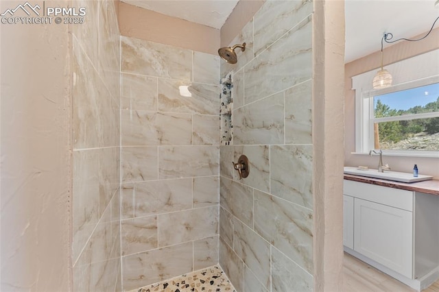 bathroom with a tile shower and vanity