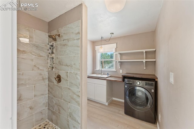 clothes washing area with light hardwood / wood-style floors, washer / dryer, and sink