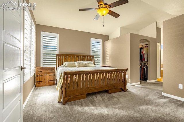 bedroom with lofted ceiling, ceiling fan, carpet, a walk in closet, and a closet