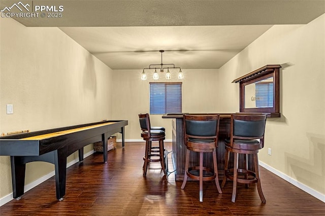 bar with dark hardwood / wood-style floors, a chandelier, and decorative light fixtures