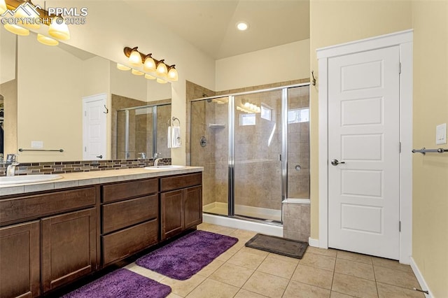 bathroom with tile patterned flooring, vanity, lofted ceiling, and walk in shower