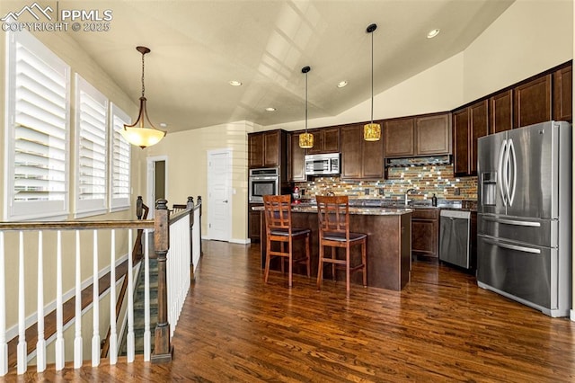 kitchen with sink, a kitchen bar, hanging light fixtures, a center island, and stainless steel appliances