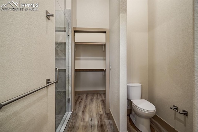 bathroom featuring hardwood / wood-style floors, toilet, and a shower with shower door