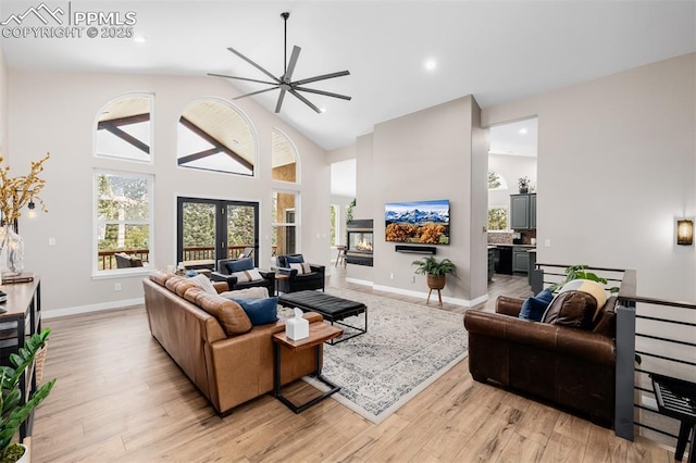 living room with ceiling fan, french doors, high vaulted ceiling, and light wood-type flooring