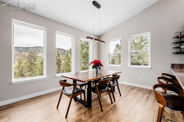 dining room featuring a mountain view, lofted ceiling, and light hardwood / wood-style flooring