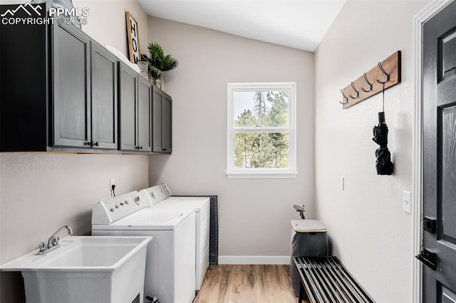 laundry area featuring washer and dryer, sink, cabinets, and light hardwood / wood-style flooring