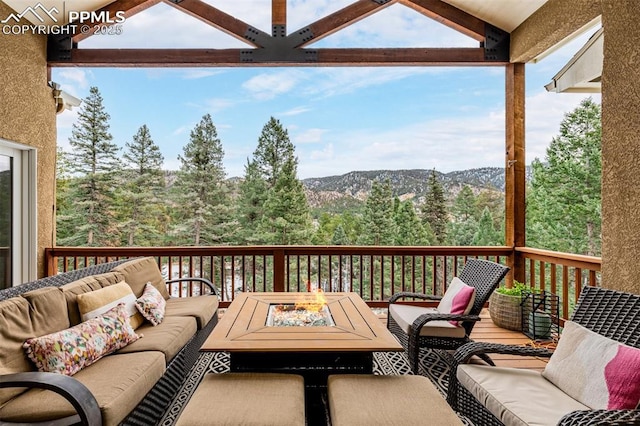 wooden deck featuring a mountain view and an outdoor living space with a fire pit