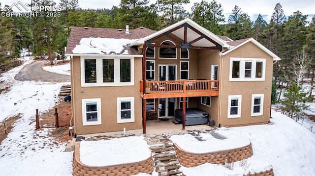 snow covered house with a hot tub and a deck