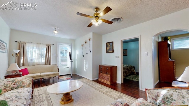 living room with ceiling fan, dark hardwood / wood-style flooring, and a textured ceiling