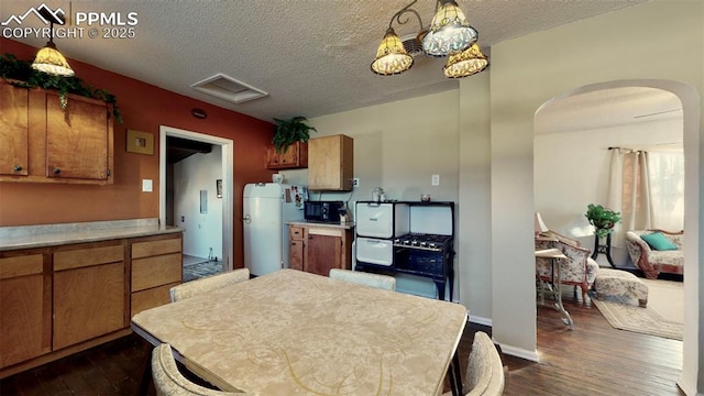 kitchen featuring a textured ceiling, dark hardwood / wood-style flooring, and decorative light fixtures