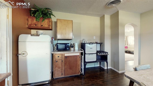 kitchen with dark hardwood / wood-style flooring, a textured ceiling, and fridge