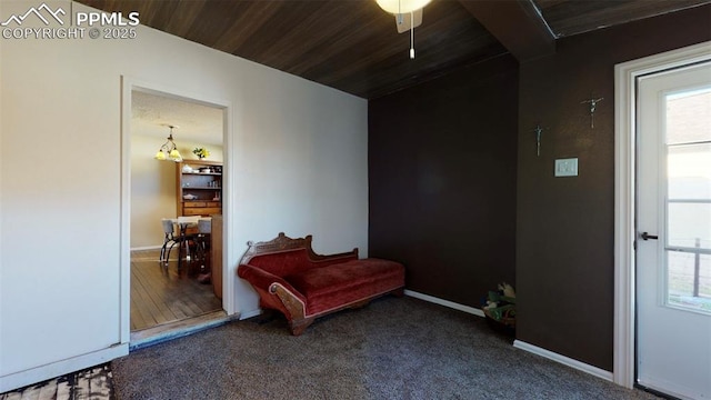 living area featuring carpet flooring, wood ceiling, and ceiling fan with notable chandelier