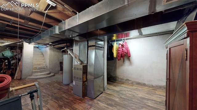 basement with dark hardwood / wood-style flooring, heating unit, and water heater