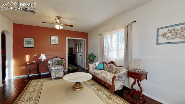 living area featuring ceiling fan and dark wood-type flooring