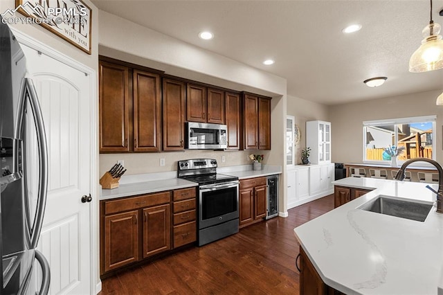 kitchen with pendant lighting, sink, appliances with stainless steel finishes, dark hardwood / wood-style flooring, and beverage cooler