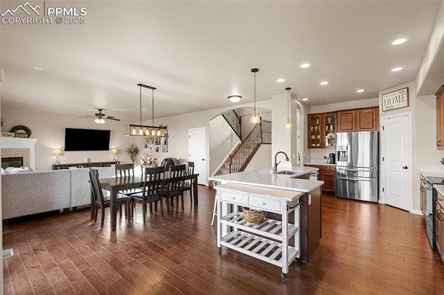 kitchen featuring ceiling fan, sink, dark wood-type flooring, a center island with sink, and appliances with stainless steel finishes