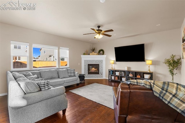 living room featuring ceiling fan, dark hardwood / wood-style flooring, and a tiled fireplace