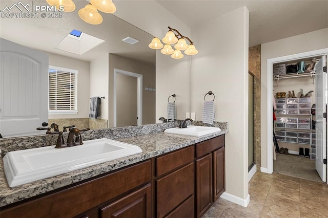 bathroom with vanity, a skylight, and a shower with door