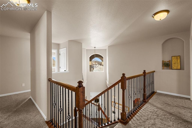 corridor with a textured ceiling and dark carpet