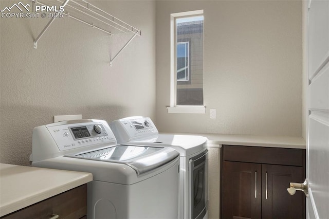 washroom with washing machine and clothes dryer and cabinets