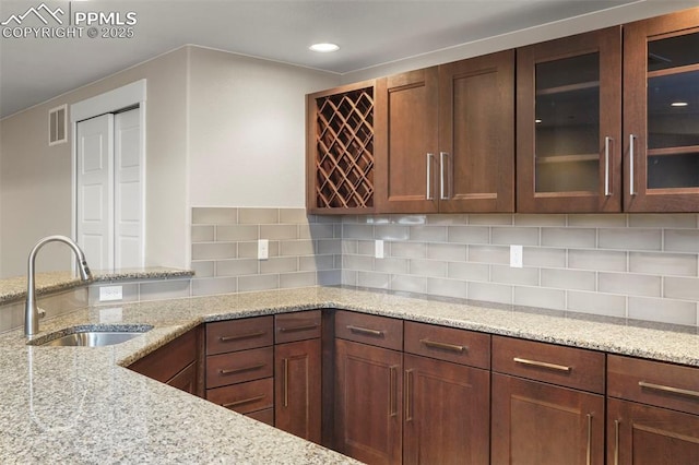 kitchen with light stone countertops, sink, and tasteful backsplash