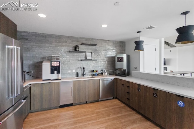 kitchen with pendant lighting, sink, decorative backsplash, appliances with stainless steel finishes, and dark brown cabinetry