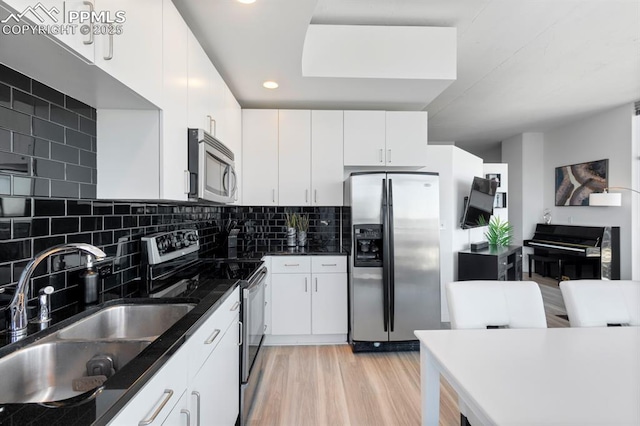 kitchen with sink, decorative backsplash, light wood-type flooring, white cabinetry, and stainless steel appliances