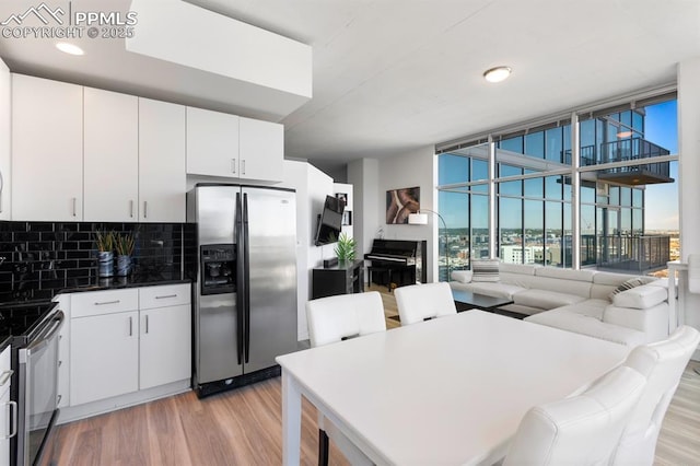 kitchen featuring decorative backsplash, white cabinetry, stainless steel appliances, and light wood-type flooring