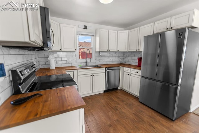 kitchen with appliances with stainless steel finishes, dark wood-type flooring, sink, white cabinets, and butcher block countertops