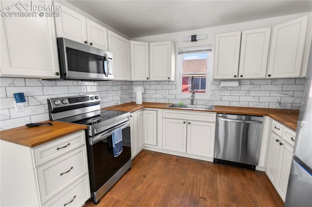 kitchen featuring sink, stainless steel appliances, wooden counters, backsplash, and white cabinets