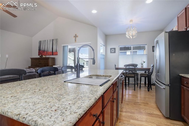 kitchen with appliances with stainless steel finishes, a wealth of natural light, lofted ceiling, and sink