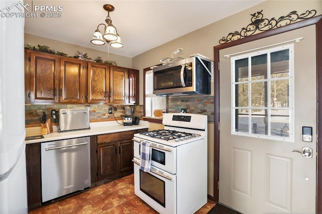 kitchen with appliances with stainless steel finishes, a notable chandelier, decorative backsplash, and hanging light fixtures