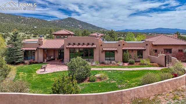 back of property with a mountain view, a lawn, and a patio