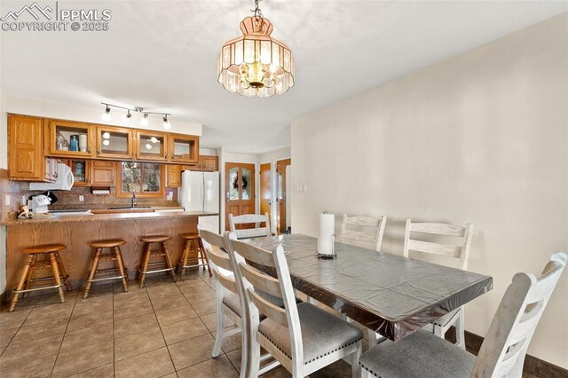 dining space with dark tile patterned flooring, sink, and a chandelier