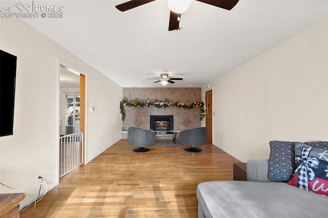 living room featuring ceiling fan, light wood-type flooring, and a wood stove