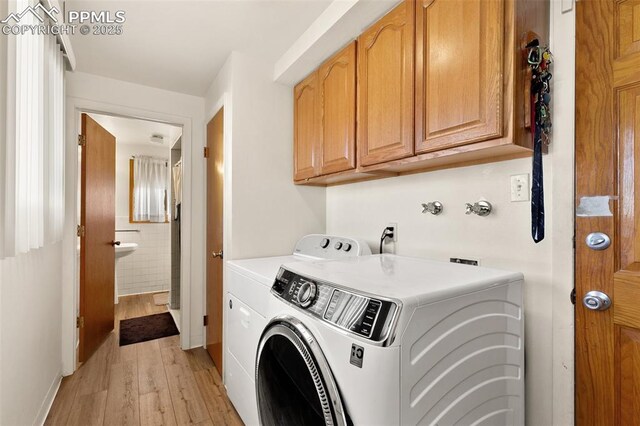 laundry room with washer and clothes dryer, light hardwood / wood-style floors, and cabinets