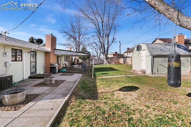 view of yard featuring a patio, central AC unit, and a storage unit