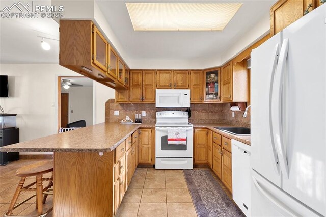 kitchen with sink, kitchen peninsula, white appliances, a kitchen bar, and light tile patterned flooring