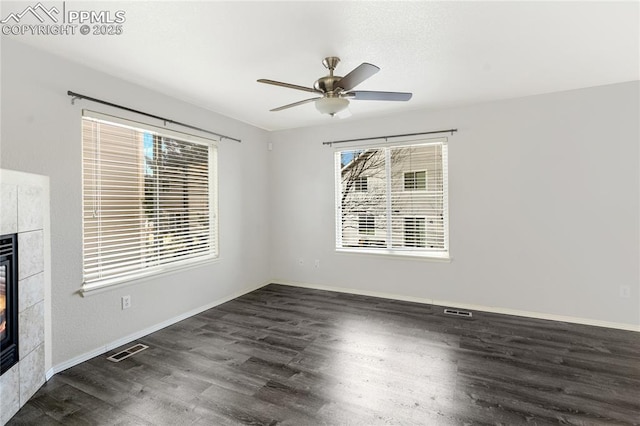 interior space with a tile fireplace, ceiling fan, and dark wood-type flooring