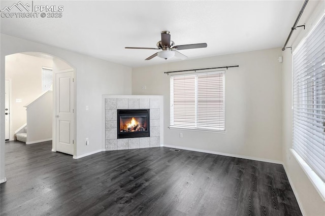 unfurnished living room featuring dark hardwood / wood-style floors, ceiling fan, and a tile fireplace