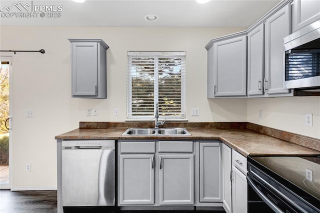 kitchen with gray cabinetry, dark hardwood / wood-style floors, sink, and appliances with stainless steel finishes