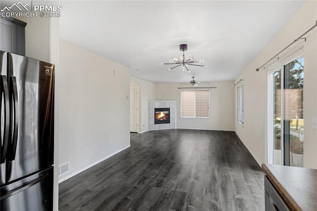 unfurnished living room with a fireplace, dark hardwood / wood-style flooring, and ceiling fan with notable chandelier