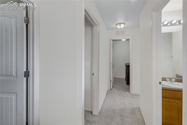 hall with light colored carpet and sink