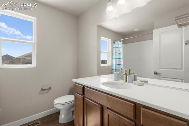 bathroom with hardwood / wood-style flooring, plenty of natural light, a shower with shower curtain, and toilet