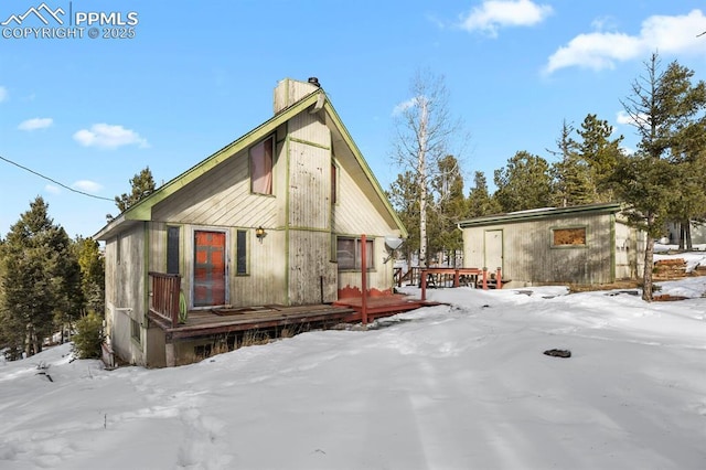 snow covered rear of property with a wooden deck