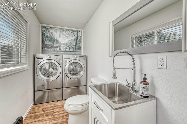 washroom with sink, light hardwood / wood-style flooring, and washing machine and clothes dryer