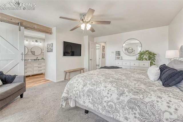 carpeted bedroom featuring connected bathroom, a barn door, ceiling fan, and sink