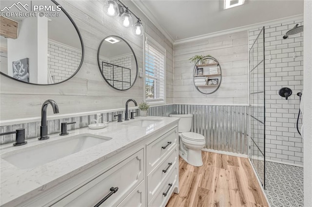 bathroom with crown molding, hardwood / wood-style floors, toilet, tiled shower, and vanity