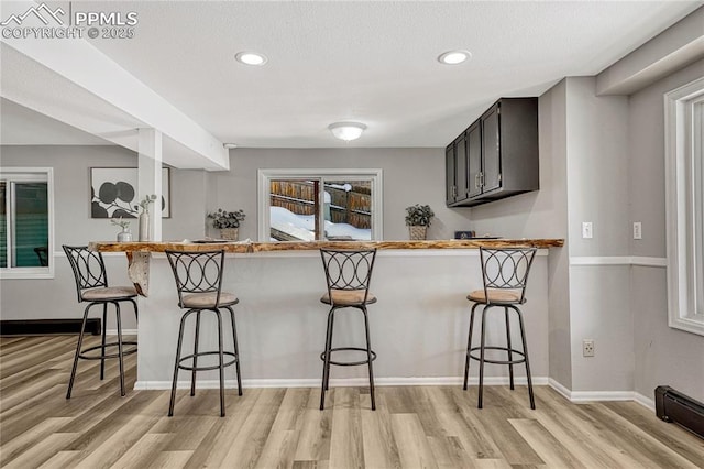 kitchen with kitchen peninsula, a kitchen breakfast bar, and light hardwood / wood-style floors