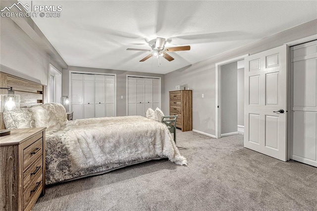 bedroom with ceiling fan, light carpet, and two closets